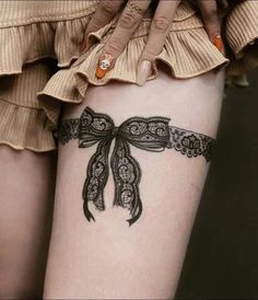 a woman's thigh with a bow tattoo on it