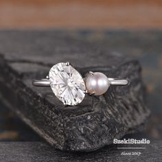 a close up of a ring with a pearl on the bottom and a diamond in the middle