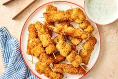 chicken skewers with toothpicks on a white plate next to a bowl of ranch dressing