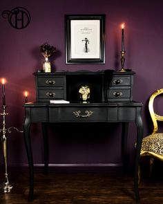 a black desk with two chairs next to it and a framed picture on the wall