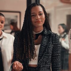 a woman with dreadlocks is walking down the street wearing a black and white jacket