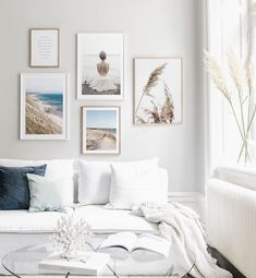 a living room filled with white furniture and pictures on the wall above it's coffee table