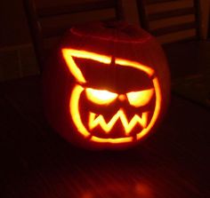 a carved pumpkin with an evil face on it's side and eyes glowing in the dark