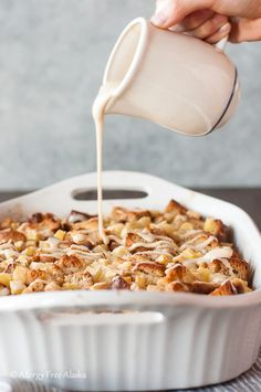 someone is pouring milk into a casserole dish filled with bread and other foods