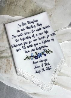 a white handkerchief with blue flowers on it sitting on top of a cloth covered table