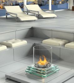 a fire pit sitting on top of a tiled floor next to lounge chairs and windows