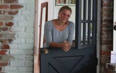 a woman standing in front of a black door