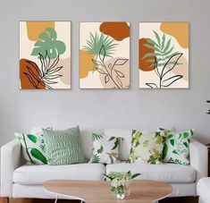 three paintings hang on the wall above a white couch and coffee table in a living room