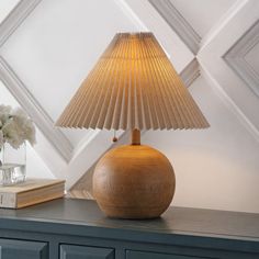 a wooden lamp sitting on top of a table next to a vase with flowers in it