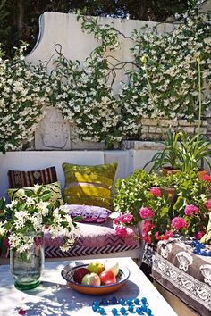 an outdoor table with flowers and fruit on it