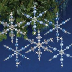 three snowflakes hanging from a christmas tree with blue and silver balls on them