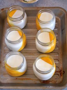 four jars filled with yogurt sitting on top of a pan