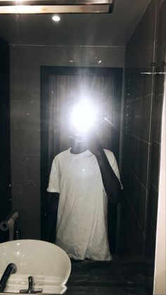 a man taking a selfie in front of a bathroom mirror with the light on