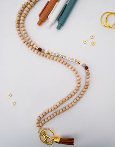 a wooden beaded necklace with beads and two gold - plated metal objects on it