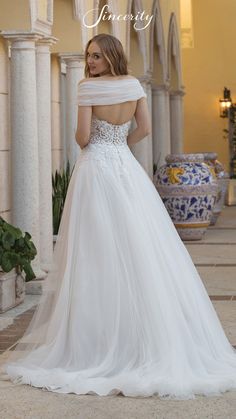 a woman in a white wedding dress standing on the ground with her back to the camera