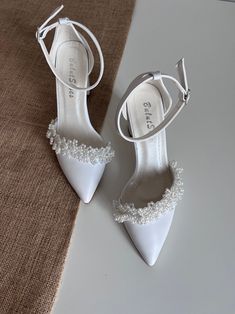 a pair of white high heeled shoes on top of a table