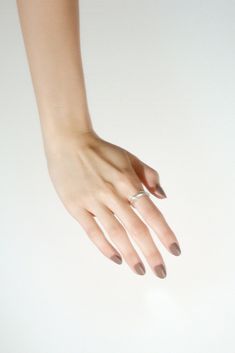 a woman's hand with a ring on her left wrist and nails in the middle