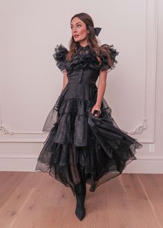 a woman in a black dress standing on a wooden floor