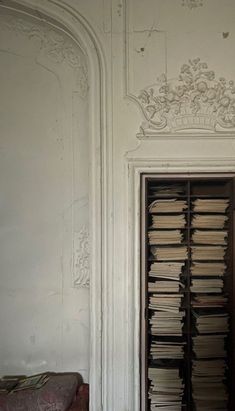 an open bookcase filled with lots of books next to a wall covered in white paint