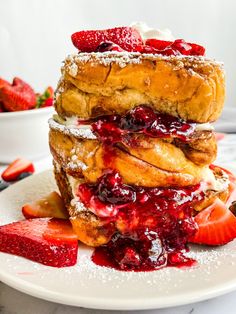 strawberry shortcakes stacked on top of each other with powdered sugar and strawberries