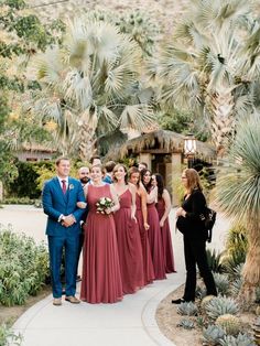 a group of people standing next to each other in front of some trees and plants