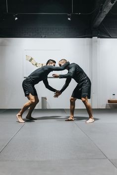 two men in black shirts and shorts are wrestling