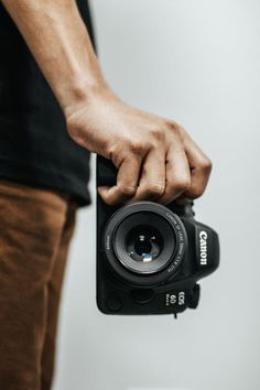 a man is holding a camera in his right hand and taking a picture with the other hand