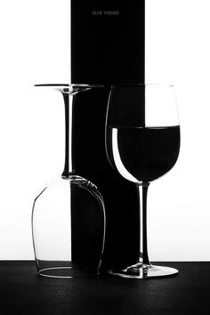 black and white photograph of two wine glasses next to each other with one glass half full