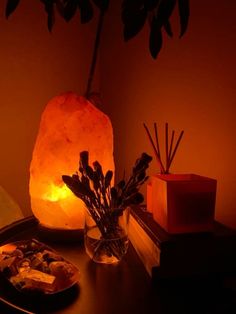 a table topped with a vase filled with flowers next to a lit candle and rocks