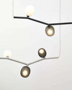 several lights hanging from a metal bar with white balls on it's end and one light in the middle