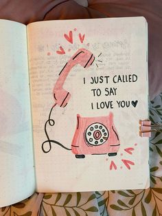 an open notebook with a drawing of a pink phone and the words i just called to say i love you