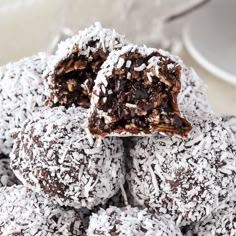 a pile of chocolate covered donuts sitting on top of a white plate with powdered sugar