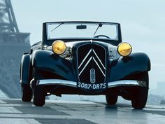 an old fashioned car is parked in front of the eiffel tower