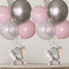 there are balloons with an elephant on them and some pink and silver balloons in the air