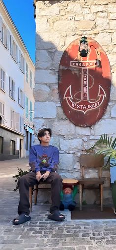 two boys sitting on chairs in front of a sign