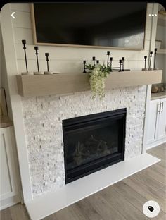 a fireplace with a tv above it and some candles on the mantels in front of it