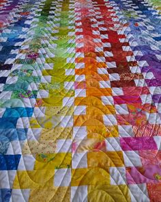 a colorful quilt is laying on top of a tablecloth that has many different colors