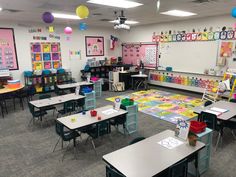 a classroom filled with lots of desks covered in colorful paper and balloons hanging from the ceiling