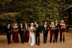 a group of people standing next to each other in front of some trees and bushes