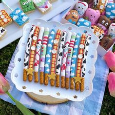 decorated cookies and marshmallows are arranged on a platter in the grass