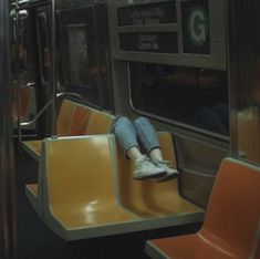 a person sitting on a subway train seat with their feet propped against the rail rails