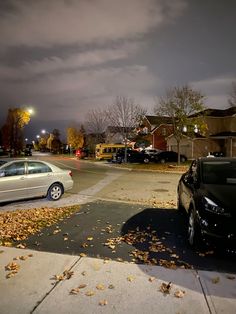 two cars are parked on the side of the road in front of some houses at night