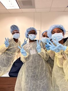 three doctors wearing protective gear and gloves standing in front of a mirror with their hands up