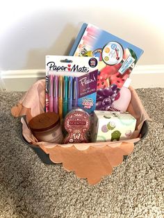 a basket filled with lots of different items on top of a carpeted floor next to a wall