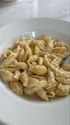 a white bowl filled with macaroni and cheese on top of a marble table