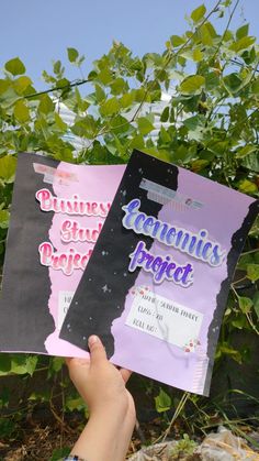 someone holding up two pamphlets in front of some plants and trees with the words geniusies project written on them