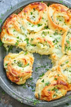 a metal pan filled with cheesy bread on top of a table