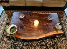 a wooden table with two candles on it in front of a couch and coffee table