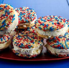 several donuts with frosting and sprinkles are on a red plate