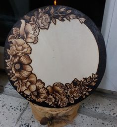 a decorative wooden box with flowers painted on the front and sides, next to a lit candle